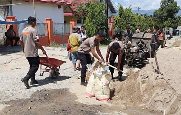 Brimob dan Warga Isimu Raya Gotong Royong Perbaiki Jalan Rusak